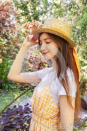 Profile photo of a brunette girl in a wicker straw hat with a ribbon in the park Stock Photo