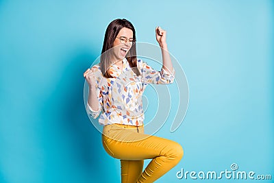 Profile photo of cute young girl raise fist knee wear spectacles geometry print shirt yellow pants isolated blue color Stock Photo