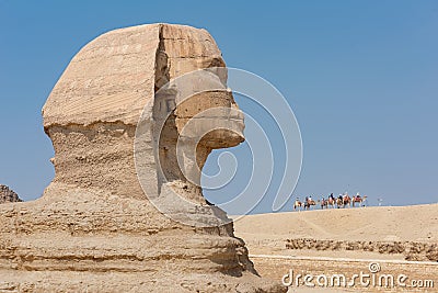 Profile Shot Of The Egyptian Sphinx With People Riding Camels In The Background Editorial Stock Photo