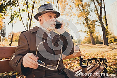 Profile side photo of amazed stupor old man rest relax autumn city center park sit bench talk family smartphone Stock Photo