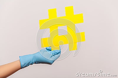 Profile side view closeup of human hand in blue surgical gloves holding yellow hashtag Stock Photo