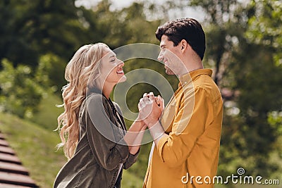 Profile side view portrait of beautiful handsome tender couple holding hands pastime honey moon outdoors Stock Photo