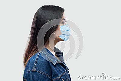 Profile side view portrait of calm serious beautiful brunette asian young woman with surgical medical mask in blue jacket standing Stock Photo
