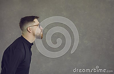 Side view of funny man pouting lips and kissing empty space on copy space background Stock Photo