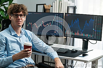 Profile of stock trader sitting against on screen, holding coffee cup. Gusher. Stock Photo