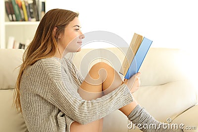 Profile of a teen reading a book at home Stock Photo