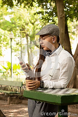 Woman with beret making an on-line purchase with smart phone Outside in park and woods. Stock Photo