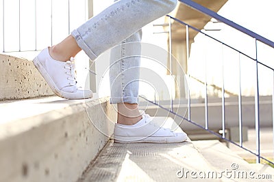 Profile of woman legs wearing sneakers walking down stairs Stock Photo