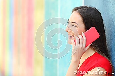 Profile of a woman talking on phone leaning in a colorful wall Stock Photo