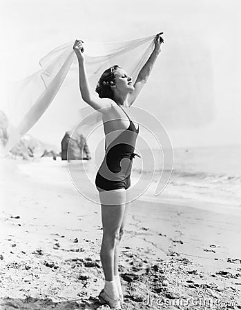 Profile of a young woman holding up a sarong at the beach Stock Photo