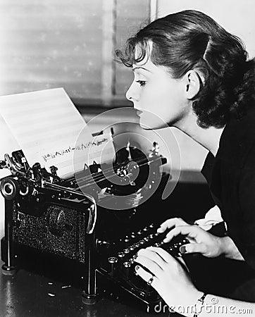 Profile of a young woman typing musical notes with a typewriter Stock Photo