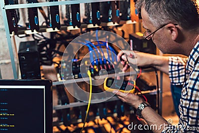 Programmer holding a wattmeter measuring cryptocurrency mining rig Stock Photo