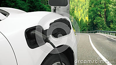 Progressive concept by electric car at the charging station on the hill road. Stock Photo
