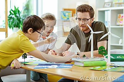 Concentrated bearded teacher spending time with his curious pupils Stock Photo