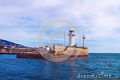 Promenade with a large lighthouse in the middle of the sea. Stock Photo