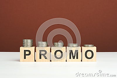 promo text on wooden blocks with coins on brown background Stock Photo