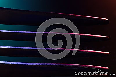 Prongs of one fork in colorful illumination macro shot creating an abstract composition suitable as a background Stock Photo
