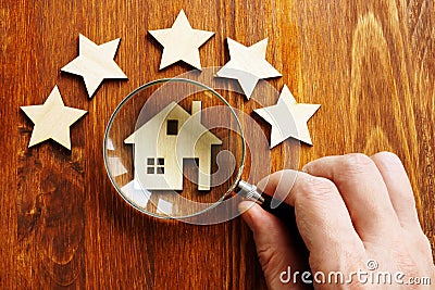 Property assessment concept. Hand holds magnifier, model of home and 5 stars Stock Photo
