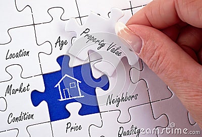 Property Value - female hand with real estate puzzle Stock Photo