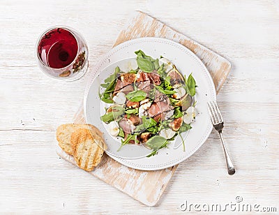 Prosciutto, arugula, figs salad with bread and glass of red Stock Photo