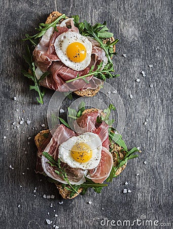 Prosciutto, arugula, and fried quail eggs sandwich. Delicious breakfast, snack or appetizer Stock Photo