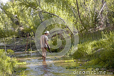 Prospector man uses a metal detector to look for lost gold treasure from the Walnut Grove Dam disaster in the Hassayampa River Stock Photo