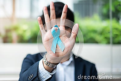 Prostate Cancer Awareness month, Business Man holding light Blue Ribbon with mustache for supporting people living and illness. Me Stock Photo