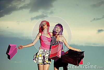 Prostitutes. Girls with artificial hair with colorful shopping bag. Stock Photo