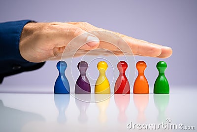 Protect Inclusion And Equality. Protect Colored Pawns Stock Photo