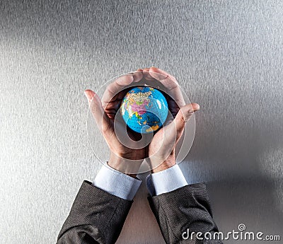 Protecting businessman holding the earth within hands for environment care Stock Photo