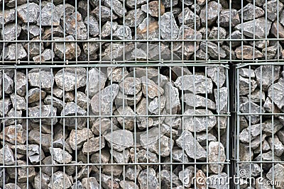 Protective gabions with grey broken stones behind grid as solid fence and solid wall and decorative element in gardens with rough Stock Photo