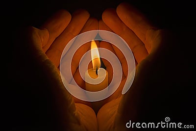 Protective hands around a burning candle Stock Photo