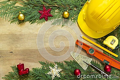 Protective helmet, mason tools and Christmas decorations on wooden background Stock Photo