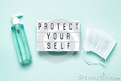 Protective mask and antibacterial gel or soap and PROTECT YOURSELF written on light board. Protecting yourself and others during Stock Photo