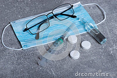 Protective mask and syringe, pills, injection and vaccine. Concept of vaccination, Covid-19 coronavirus diagnostic, cure for flu Stock Photo