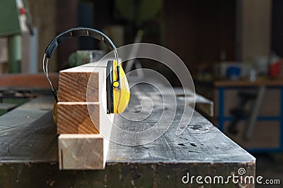 Protective yellow headphone on wooden prism in joinery Stock Photo