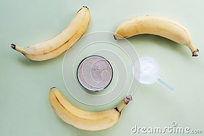 Protein powder and cocktail in a glass and banana on light green background. Healthy food. Top view, flat lay Stock Photo