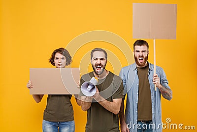 Protesting young three people guys girl hold protest signs broadsheet blank placard on stick screaming in megaphone Stock Photo