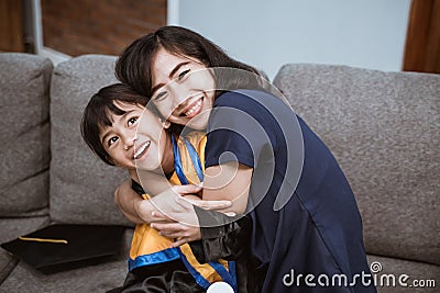 proud asian mother embrace her daughter during elementary school graduation day Stock Photo