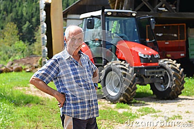 Proud farmer standing in front of his tractor Stock Photo