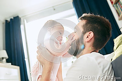 Proud father holding his newborn baby daughter up in the air at home Stock Photo