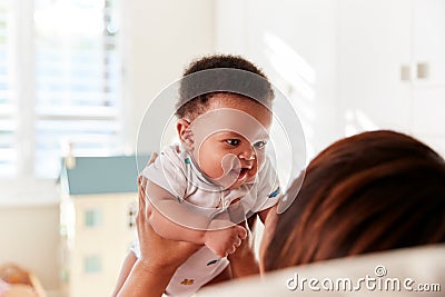 Proud Grandmother Cuddling Baby Grandson In Nursery At Home Stock Photo