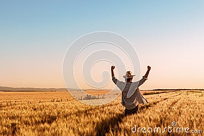 Proud happy victorious wheat farmer with hands raised in V Stock Photo