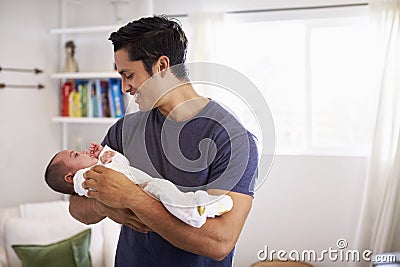 Proud Hispanic father holding his four month old child at home, waist up Stock Photo