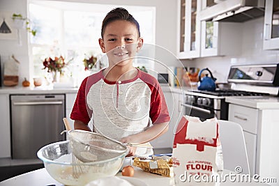 Proud pre-teen boy making cake mixture on his own in the kitchen, smiling, close up Stock Photo