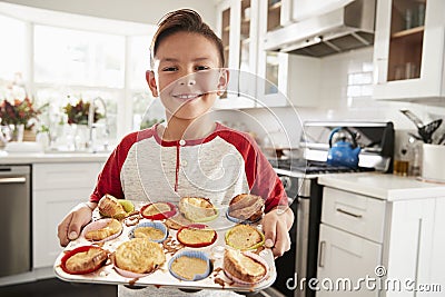 Proud pre-teen Hispanic boy standing in kitchen presenting the cakes heï¿½s made to camera, close up Stock Photo