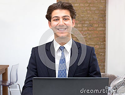Proud smiling young businessman at his desk Stock Photo