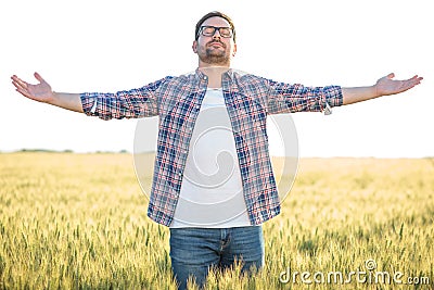 Proud young millennial farmer standing in wheat field with arms outstretched Stock Photo