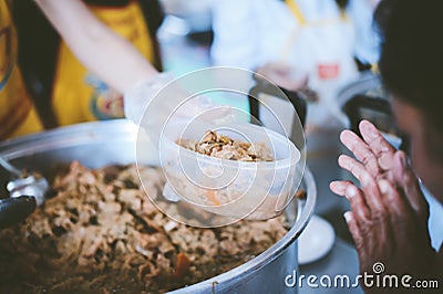 Providing free food to the poor : The hands of beggars receive donated food Stock Photo