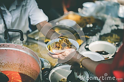Providing free food to the poor : The hands of beggars receive donated food Stock Photo